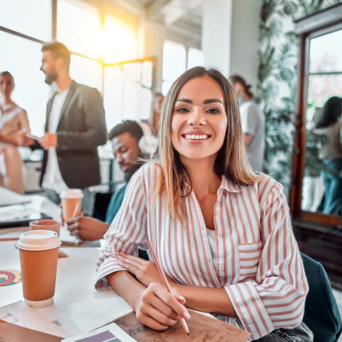 Smiling female employee sit in coworking space and working on the project